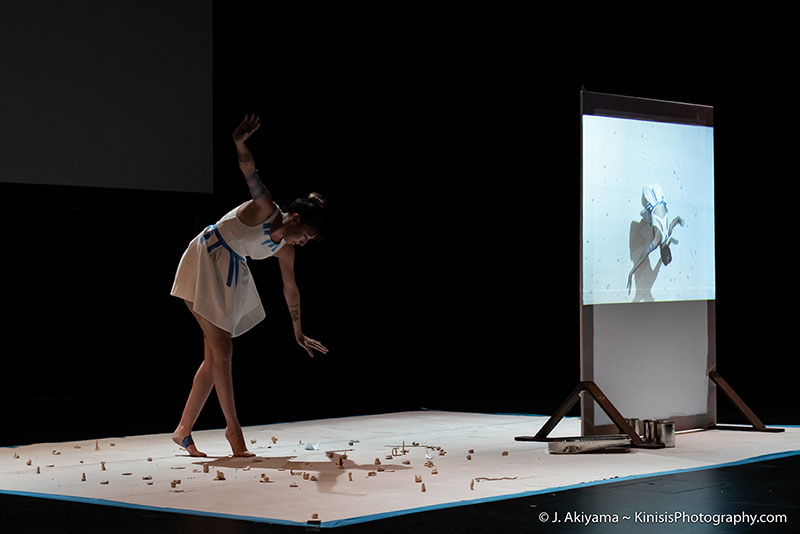 a dancer wobbling, trying not to step on the clay figurines she's surrounded by, while another surface shows a projection of her from a bird's eye view
