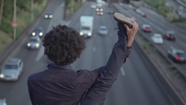 a dancer holds a leg above his head, looking down at a freeway