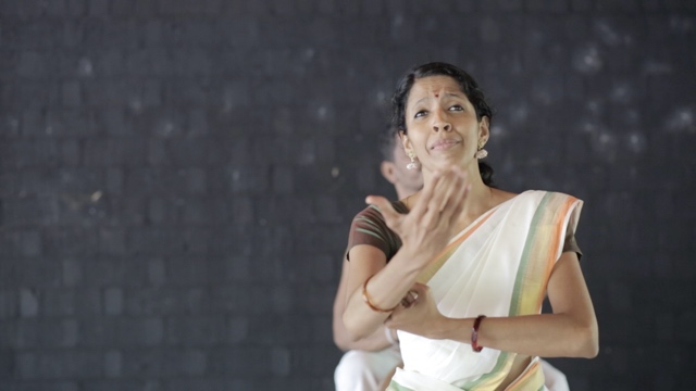 an Indian dancer emotes dramatically, reaching an arm toward the camera