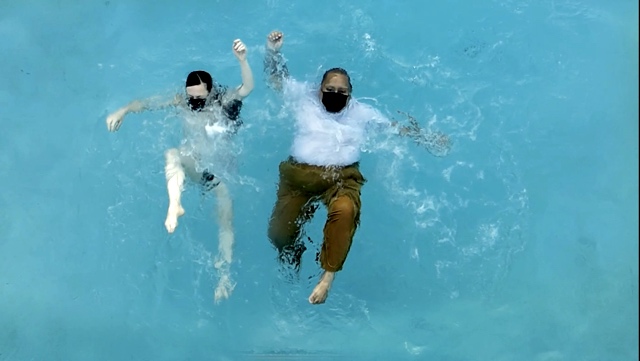 two dancers falling backward into a pool as waves ripple