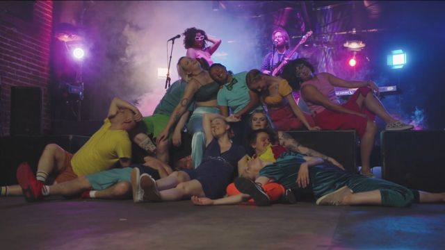 ten dancers in brightly colored clothing collapse on a stage