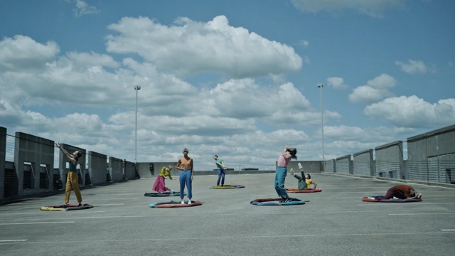 seven dancers are encircled by fabric sculptures on a parking garage roof