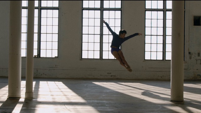 an Asian American man in mid air in a balletic jump