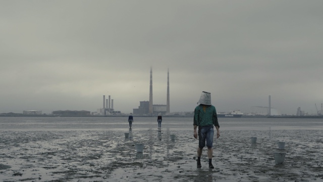 one dancer in the foreground and two in the background with buckets on their heads