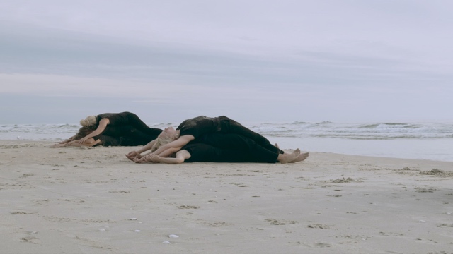 two piles of dancers lying on top of one another on the beach