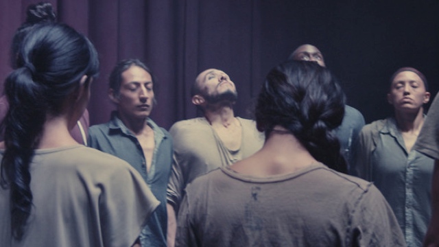 a group of male and female dancers with eyes closed, holding hands, mid-breath