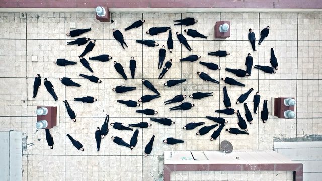 dozens of bodies clad in black from head to toe speckle a rooftop