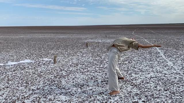 a dancer bends backward with arms splayed in a snowy open flat