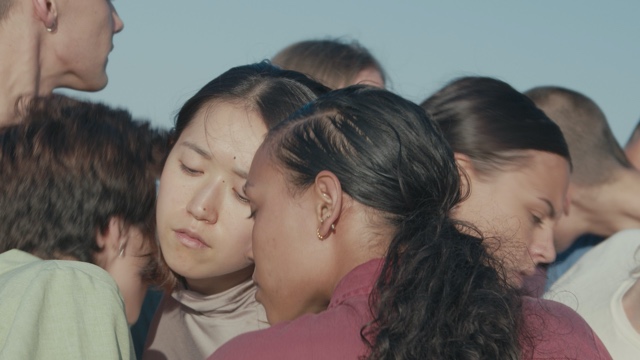 many dancers of diverse races and genders huddle closely together