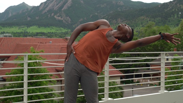 a brown-skinned, Black male dancer leans to the left looking upward