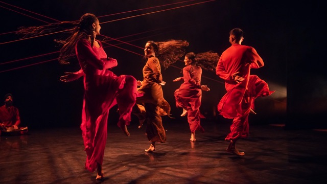 several Indian dancers caught mid turn with fabric and hair flying