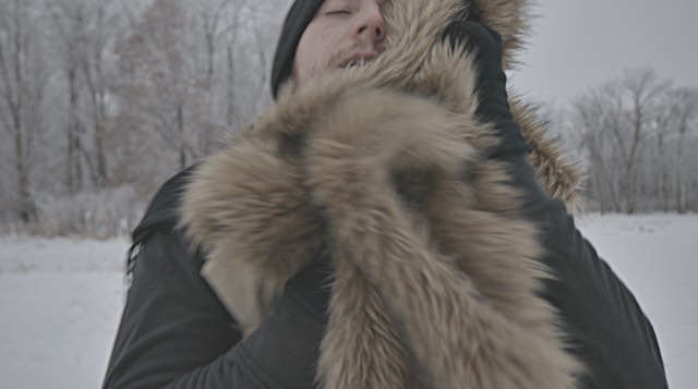 a light skinned man rubs his face in a furry coat