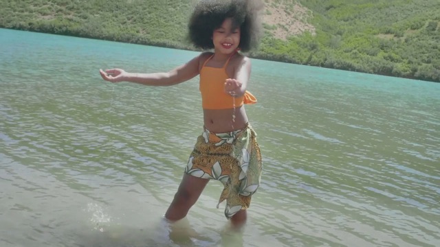 a young dancer stands in water, cupping some as it falls from her hand