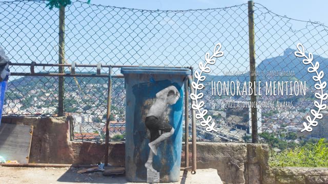 a cutout photograph of a boy dancing, superimposed on a dumpster in front of a mountain city landscape