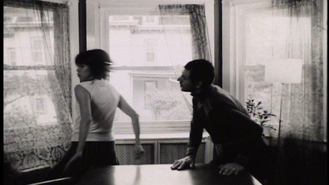 a woman spins to turn away from a man with his hands placed on a dining table