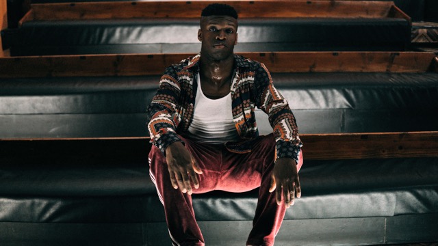 a man in red pants and a colorful jacket sits on a wide, padded staircase