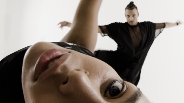 a face, upside down in the foreground, and a male dancer in black in the background