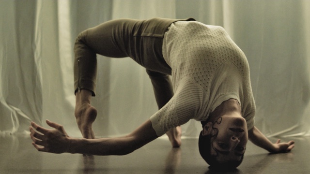 a woman does a backbend, touching only her toes, right hand, and the crown of her head to the ground