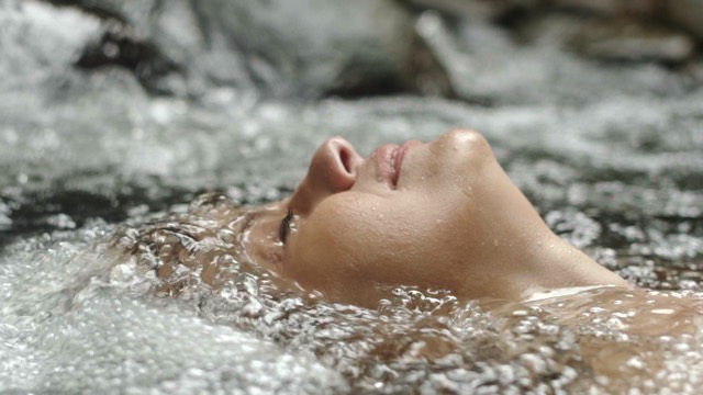 a closeup of a woman's face emerging from bubbling water