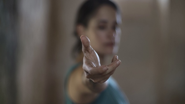 a hand, in sharp focus, extends from an out-of-focus woman