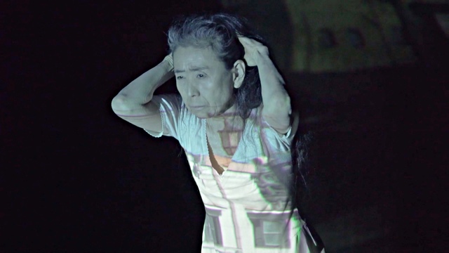 a woman pulling her hair back with a projection of a building on her body
