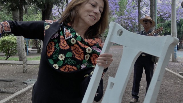 a woman in a flowery scarf dances with a white painted chair