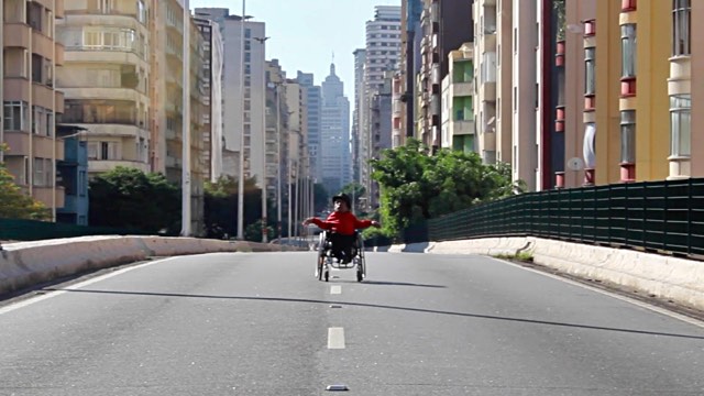a person in a wheelchair travels down the center of a city street