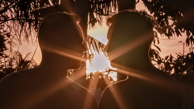 two men's silhouettes face each other with a setting sun shining brightly behind them