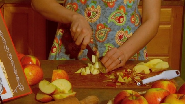 a close up of a woman's hands cutting apples