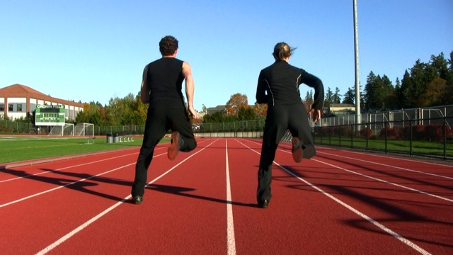 two dancers running on a track in mid stride