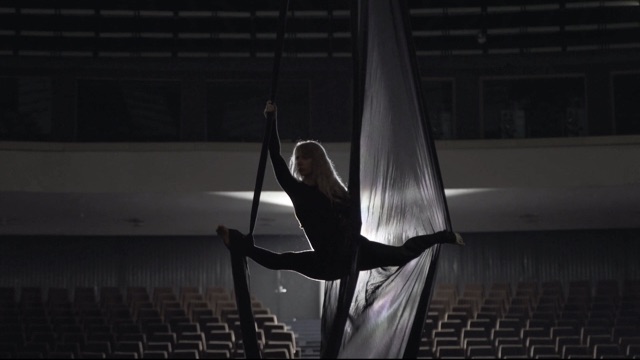 an aerial dancer in a split suspended in fabric