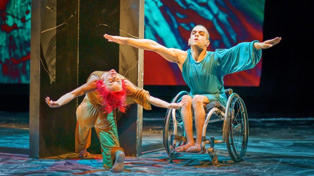 a dancer in a wheelchair with arms in a V next to a dancer in a lunge reaching back in a lunge with the same arm formation