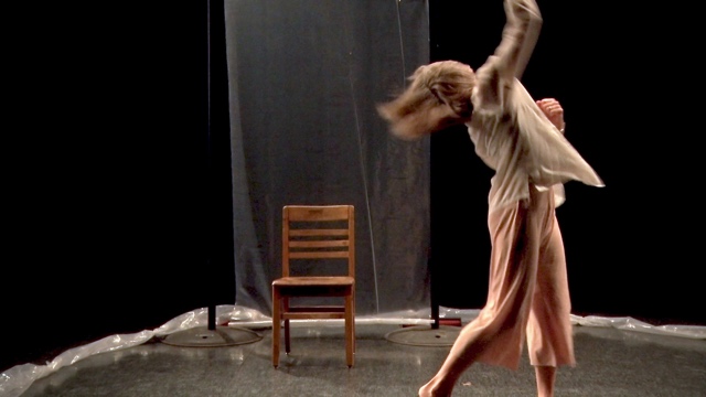 a dancer in pastel clothing throws her arm up and her head back, caught in motion