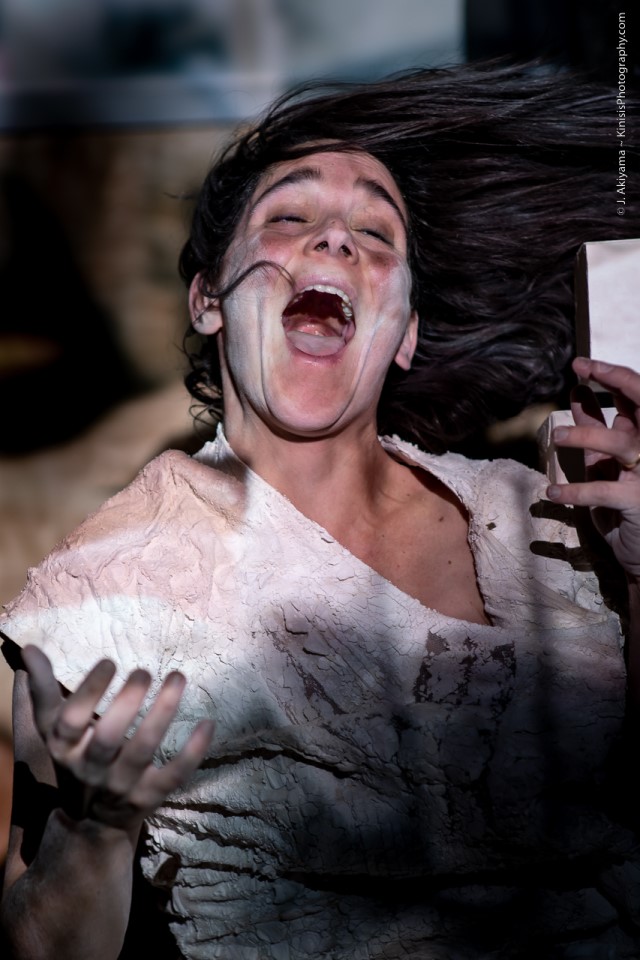 a woman covered in dried plaster and chalk yells in anguish