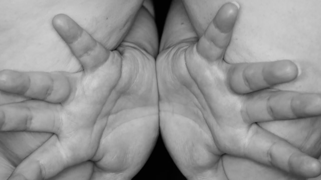 a closeup black and white photo of two hands, palms together but fingers spread apart