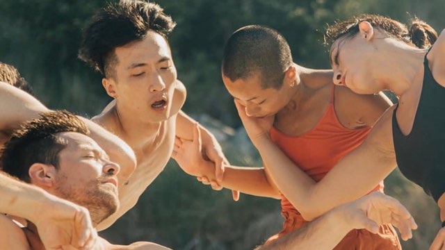 a closeup of five young people dancing in a circle outdoors in the sunlight