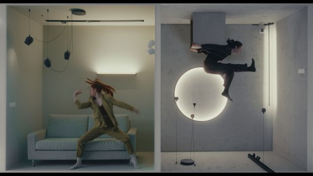 two adjacent square rooms each with a dancer moving in front of modern looking furniture - the room on the right is upside down