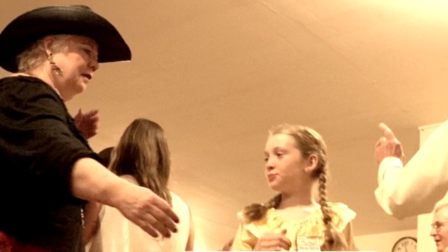 a young girl in white looks at an adult woman in a black blouse and a black hat