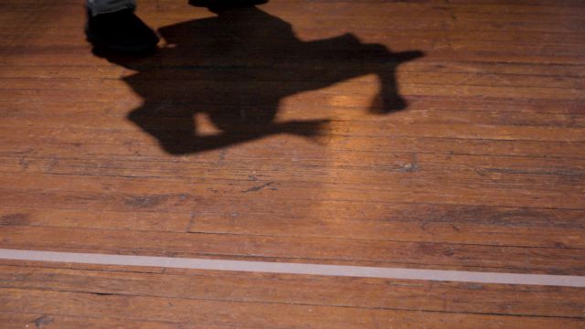 a closeup of an aged hardwood floor with a dancer's shadow
