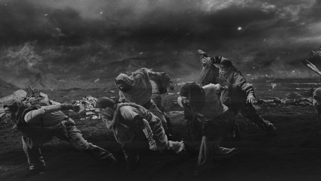a stylized photo, almost as though computer-generated, of five men in long hoods struggling to traverse a barren landscape