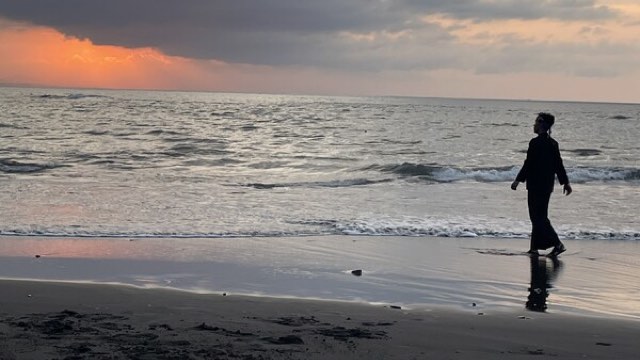 at sunset, the silhouette of a person can be seen walking along a beach