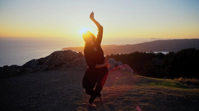 on a seaside cliff at sunset, a dancer moves gracefully as if part of the land