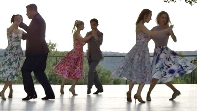 three pairs of dancers in formal dress hold hands and dance on an outdoor balcony