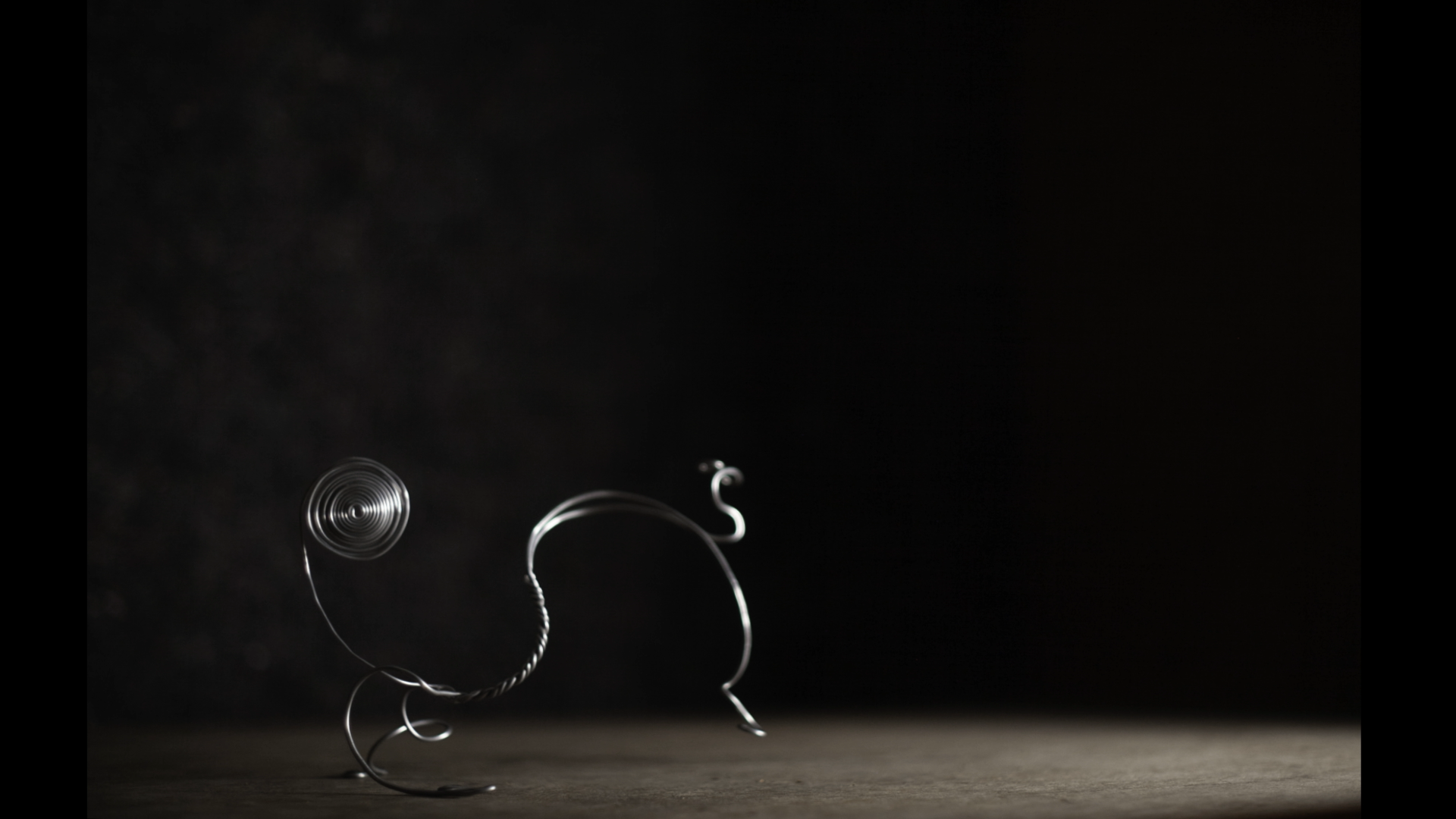 a wire puppet representing a dancer is positioned on a miniature stage, complete with stage lighting and a black backdrop