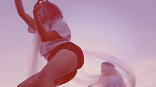 a low angle, washed out image of two dancers wearing and twirling translucent scarves